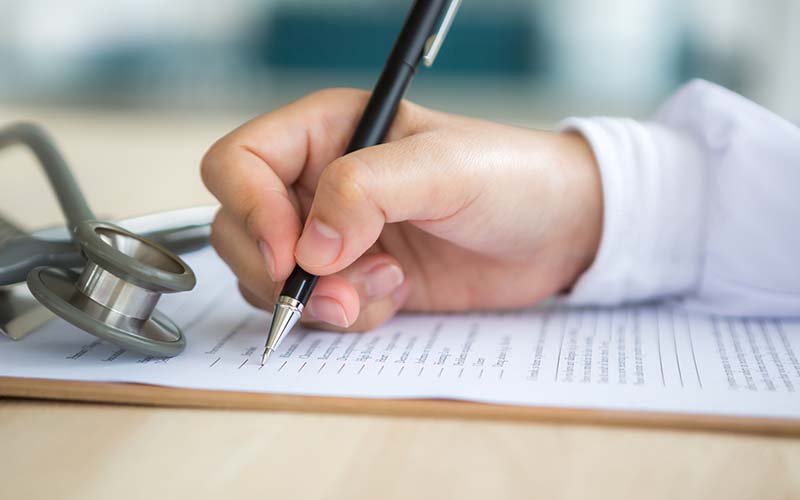 gros plan sur une main d'infirmière écrivant sur un document