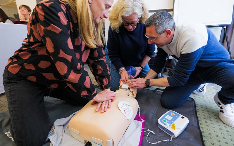 formateur utilisant un défibrillateur sur un mannequin d'exercice devant des apprenants IDEL