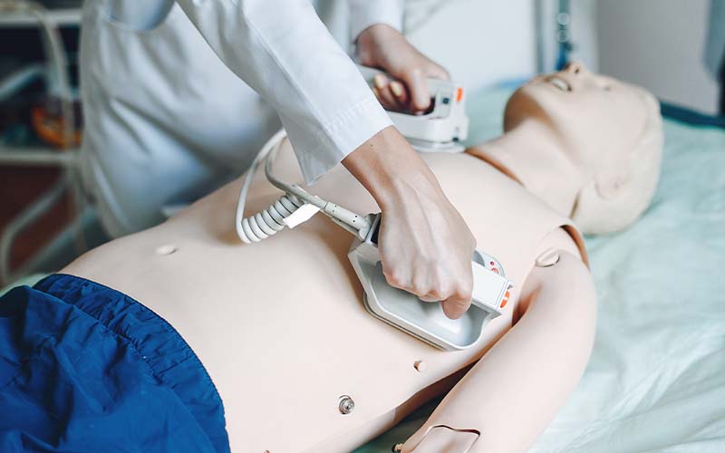 Infirmier utilisant un défibrillateur sur un mannequin d'exercice