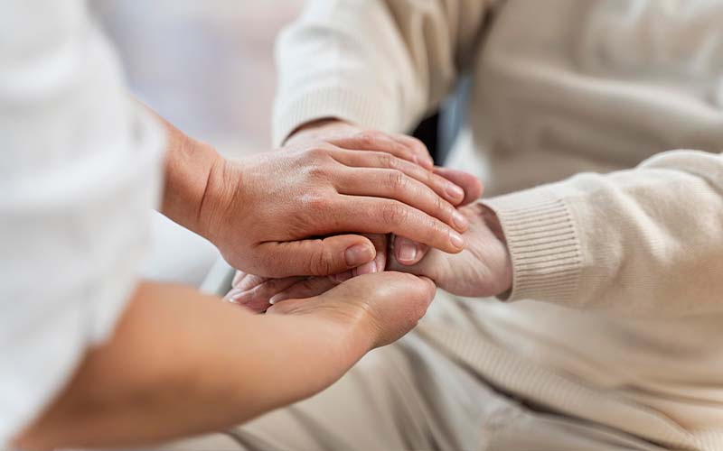 Mains d'un soignant sur des mains d'une personne agée
