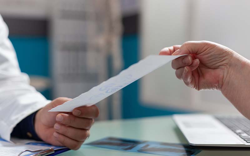 Une feuille de soin qui passe de la main d'un patient à celle d'un soignant