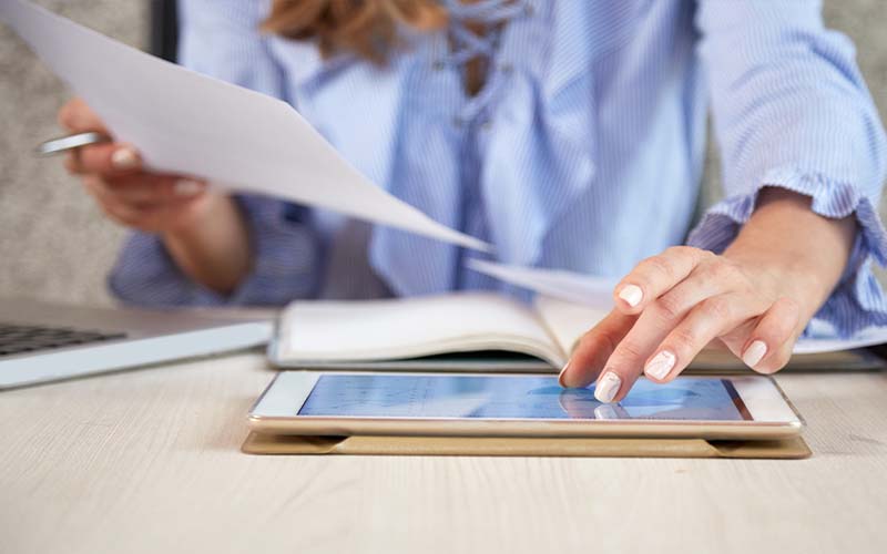 Femme en train de regarder des documents et une tablette