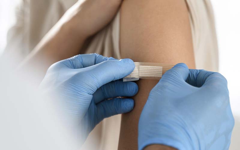 Infirmier qui applique un pansement sur le bras d'un patient après un vaccin