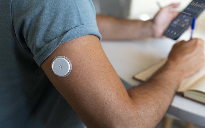Gros plan sur le bras d'un homme qui a un capteur de glucose sur le bras